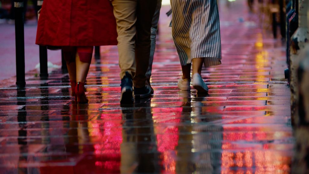 Close-up of pedestrians' feet on wet Dublin pavement at night with city lights reflecting