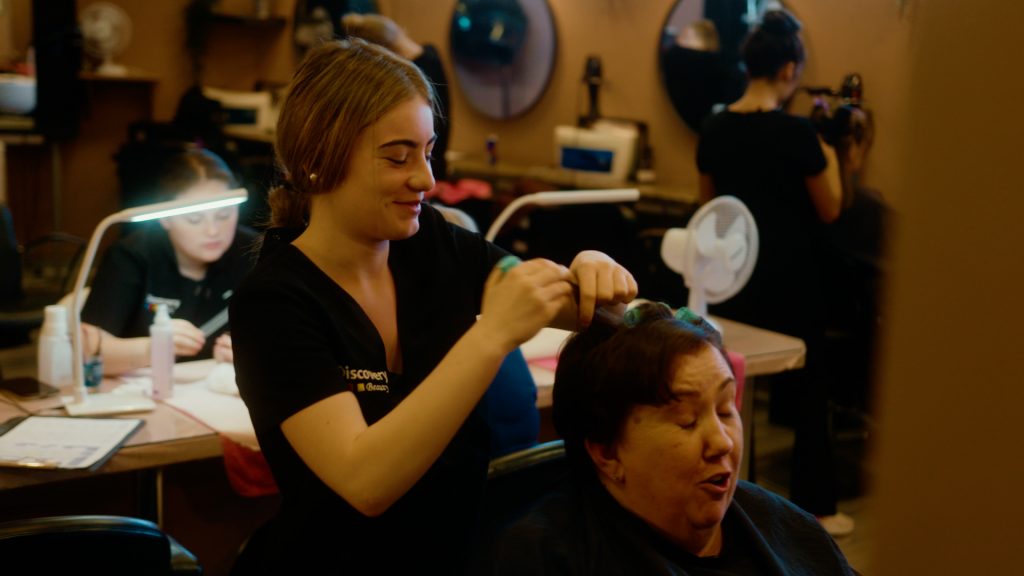 Beauty student styling hair of community member as part of hands-on training at Darndale Discovery Centre