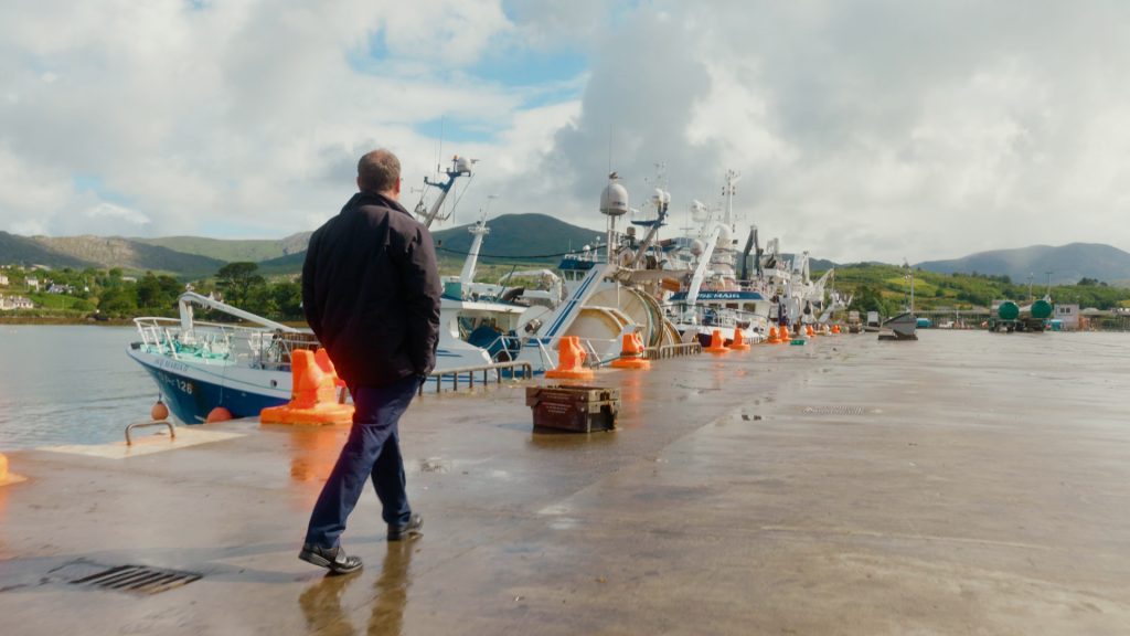 Patrick Murphy walking along peer at Castletown Bere Harbor, inspecting fishing boats
