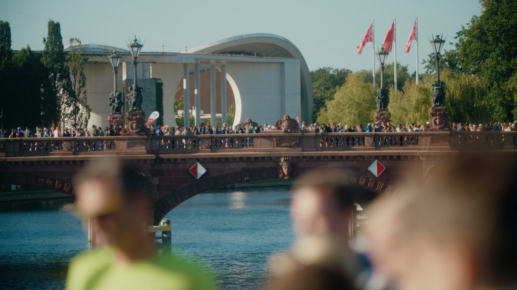 Tightly packed runners crossing Spree River bridge at Berlin Marathon, captured in telephoto shot
