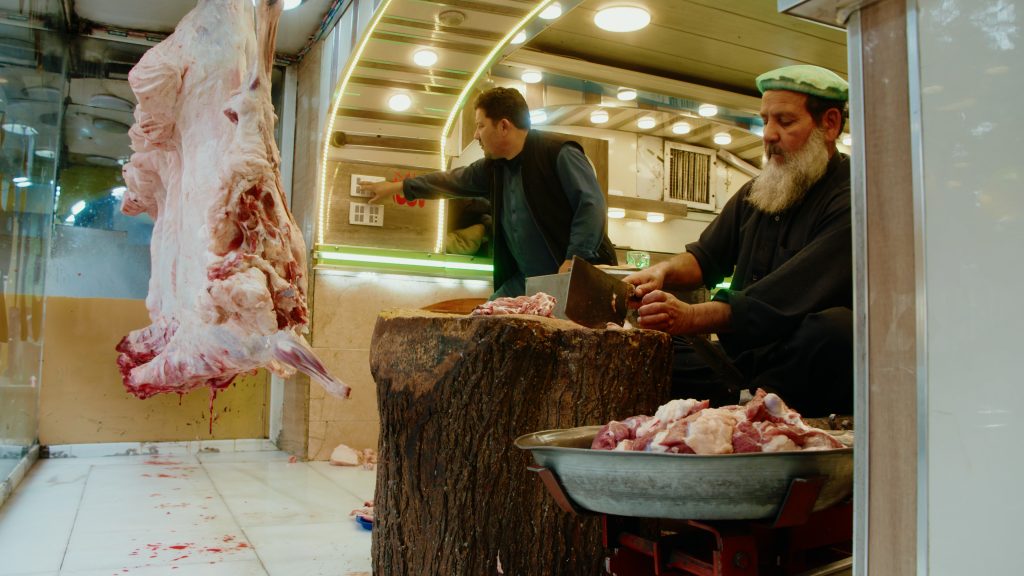 Butcher preparing meat in the windowfront of a cricket restaurant