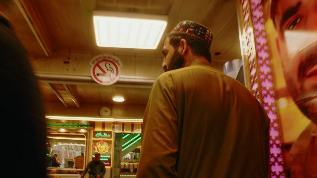 Incandescent neon tracking shot still of protagonist walking through cricket restaurant
