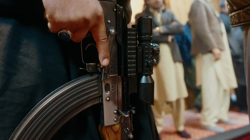 Close-up of scoped AK-47 rifle inside restaurant, safety off