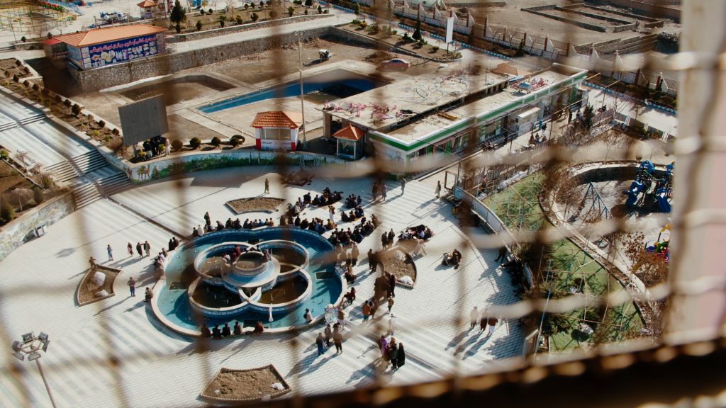 Gritty, partially obscured view from atop Ferris wheel overlooking Kabul amusement park