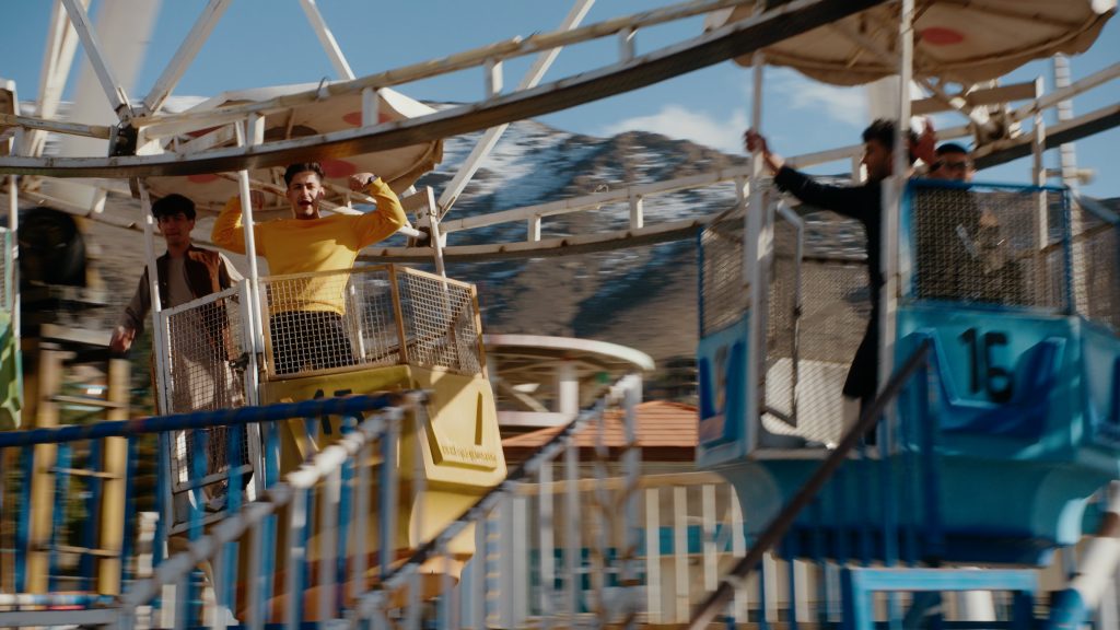 Young man riding Ferris wheel in celebratory Gulbadin Naib pose