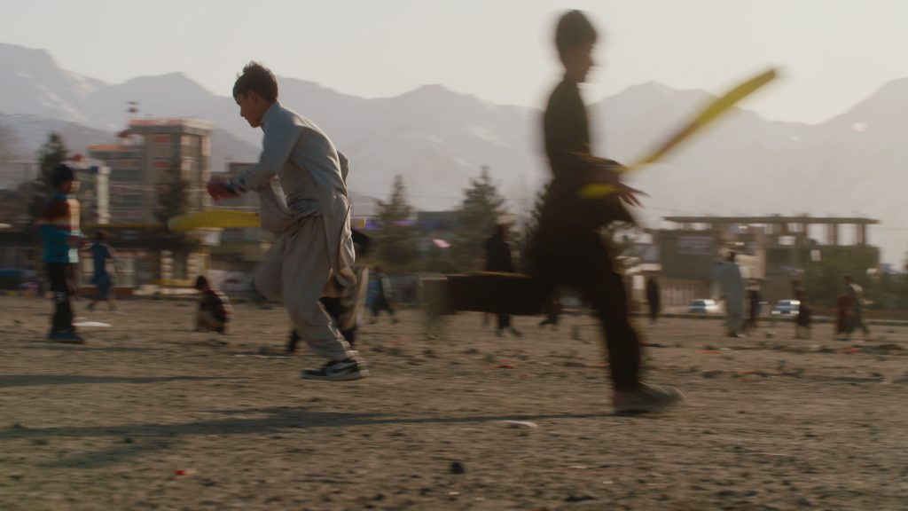Two young boys sprinting between wickets during a cricket game