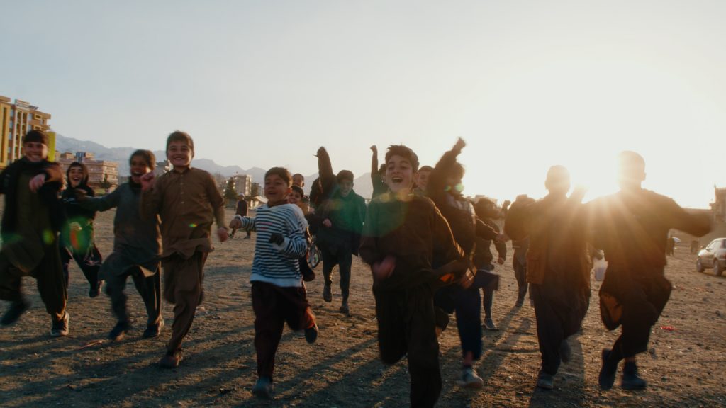 Silhouetted children running and cheering in warm backlight