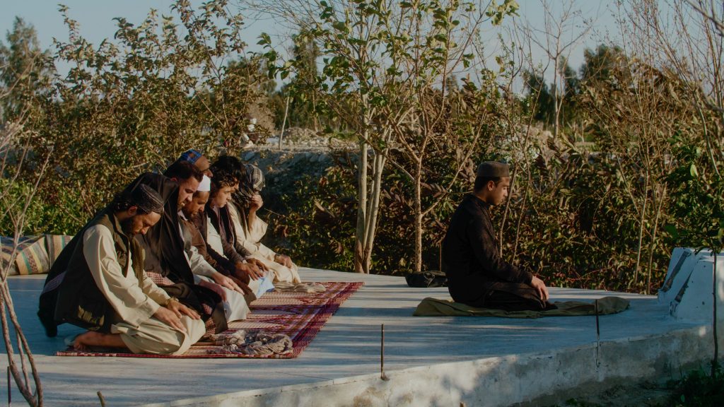 Group of Afghan men performing prayer at outdoor mosque in Nangarhar, Afghanistan