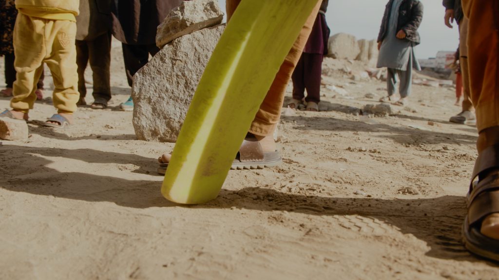 Detail shot of cricket bat in front of stone wicket during street cricket match in Afghanistan
