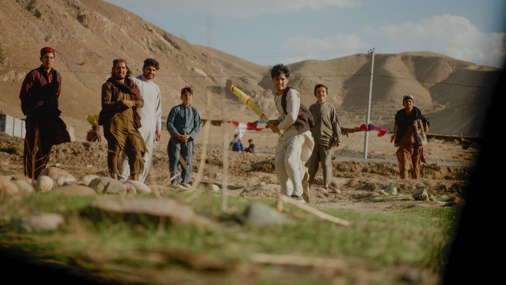 Man batting during a cricket match in the mountains of Afghanistan