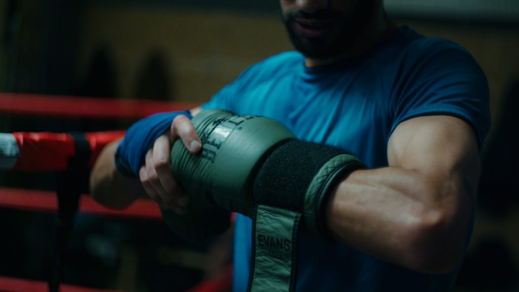 Boxer putting on glove during training session in the ring