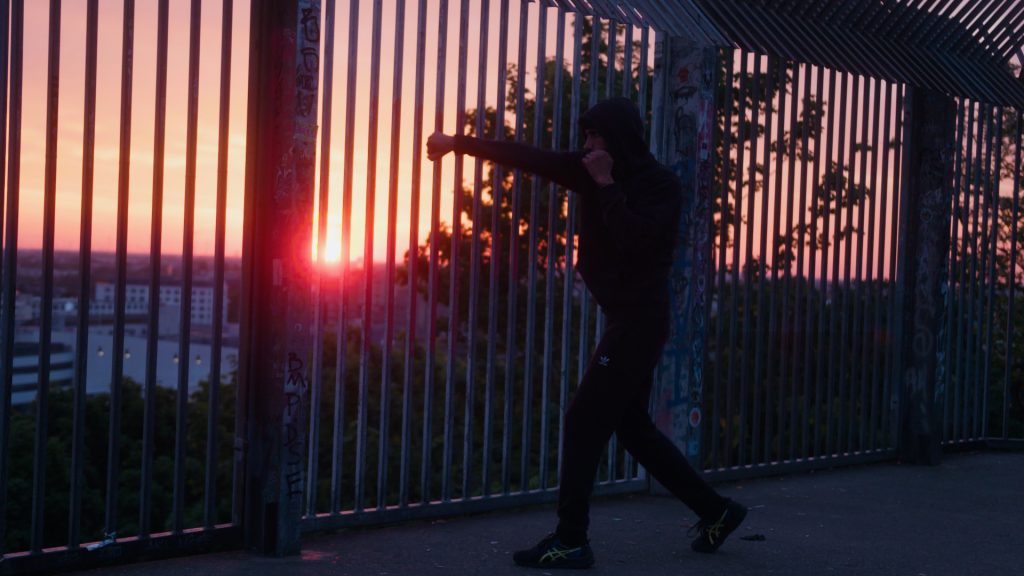Silhouetted boxer training at sunrise on Berlin hilltop in summer morning light