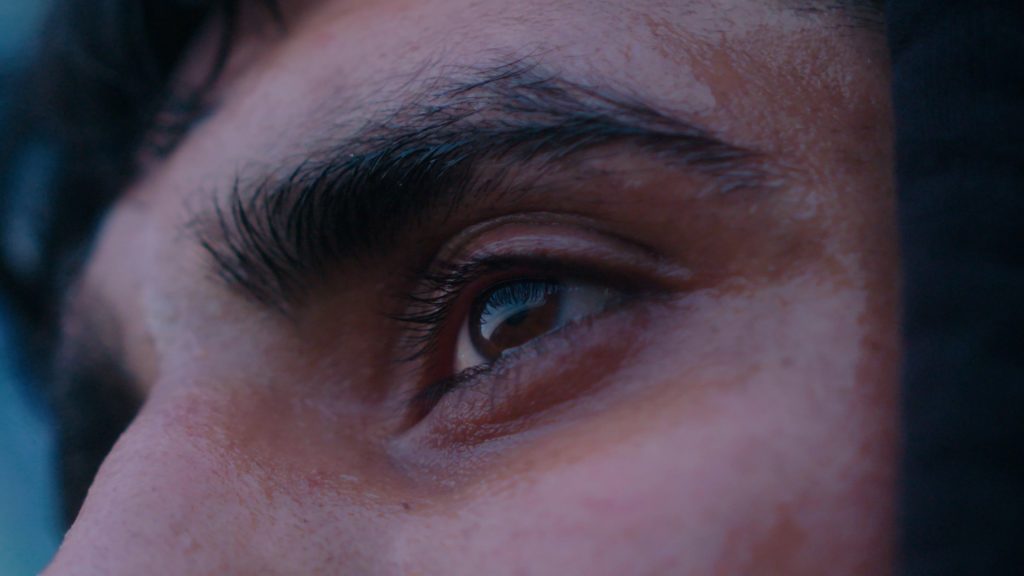 Tight shot of tired athlete’s eye, glistening with sweat and fatigue