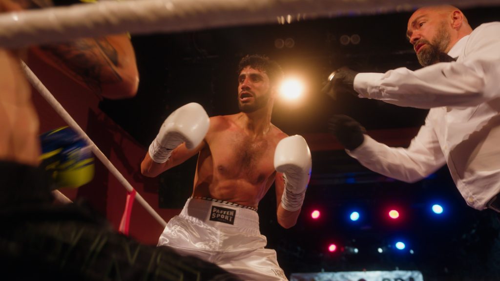 Afghan boxer Shoaib Akhtar standing over fallen opponent while referee steps in during fight