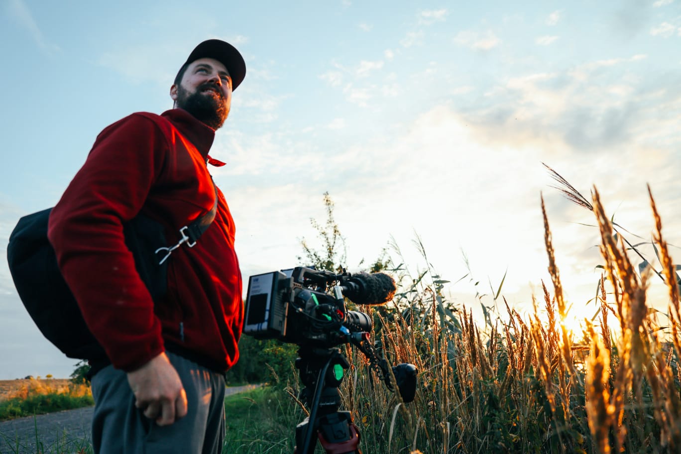 Killian Bayer capturing golden-hour lake landscapes with backlit foliage, framing atmospheric shots for a documentary production.