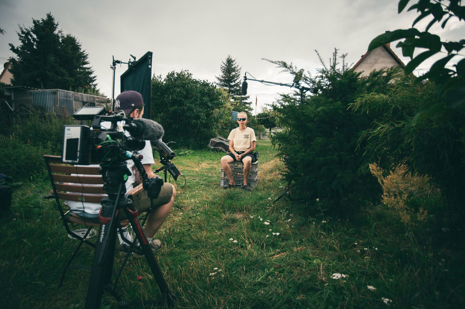 Documentary-style sit-down interview setup showing Killian Bayer interviewing the main protagonist, with professional lighting and camera equipment.